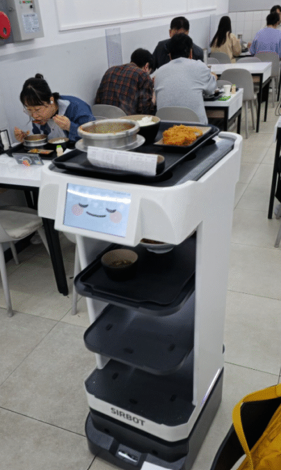 Robottitarjoilija kuljettaa annoksia asiakkaille korealaisessa lounaskahvilassa. 